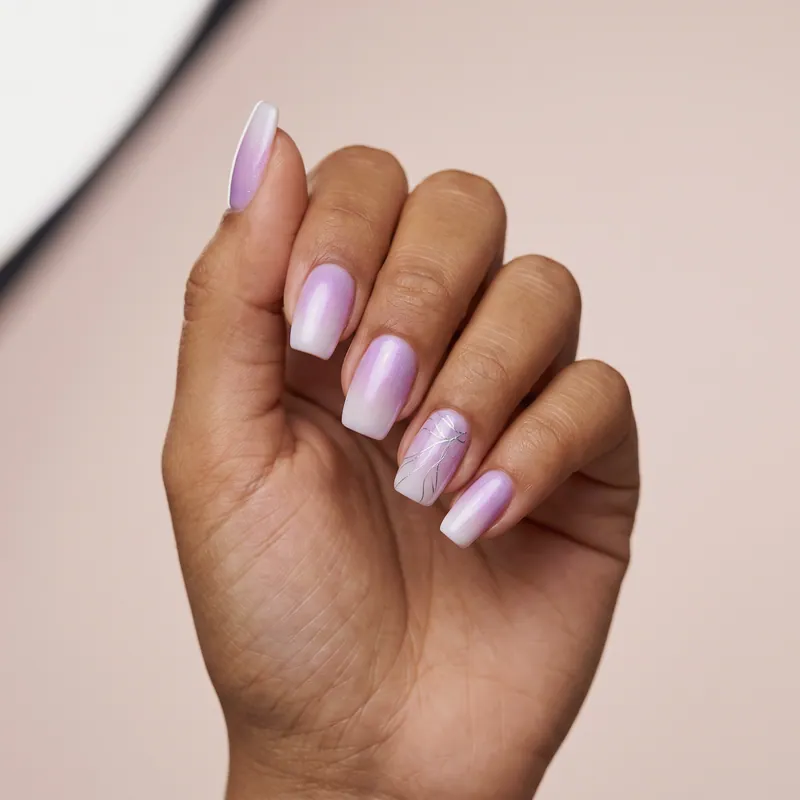 Uñas cuadradas medianas en degradado lila a blanco con brillo perlado y líneas plateadas finas en una uña