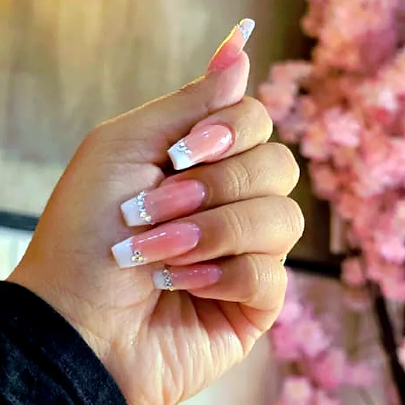 Uñas largas cuadradas con degradado de rosa a blanco perlado y una línea de cristales en la base